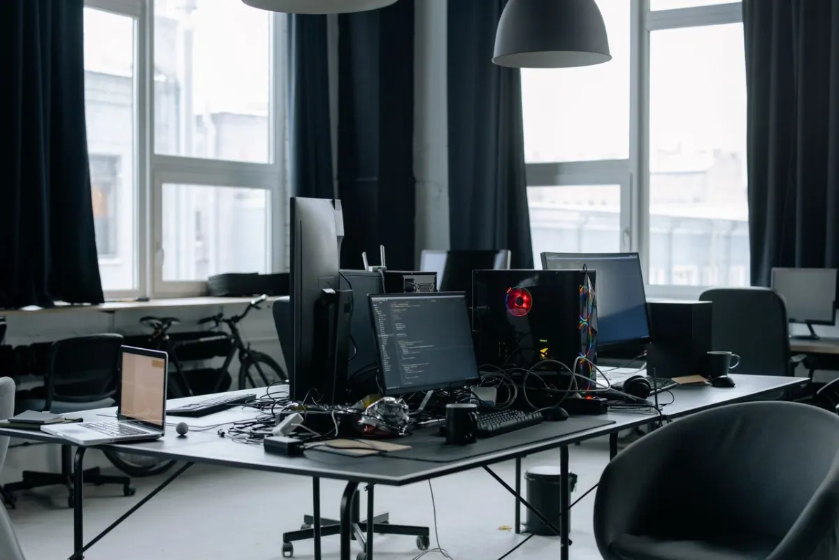 Monitors on a desk in an office, one of them showing code